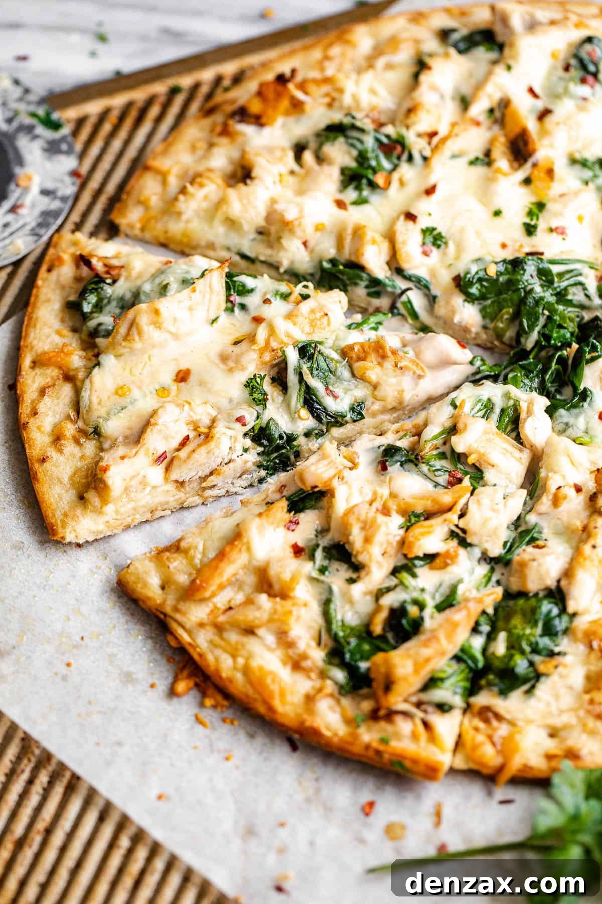 side shot of sliced chicken alfredo pizza