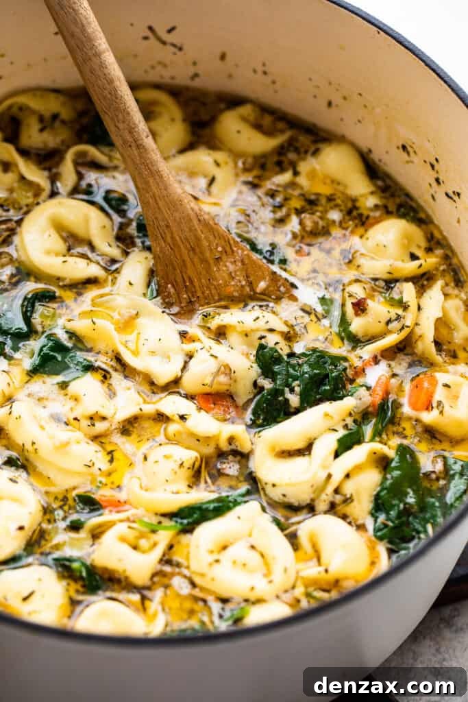 stirring through tortellini soup with a wooden spoon