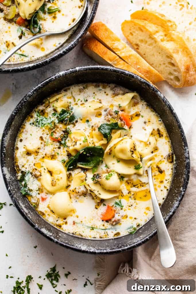 overhead shot of creamy tortellini sausage soup in a black soup bowl with a spoon inside