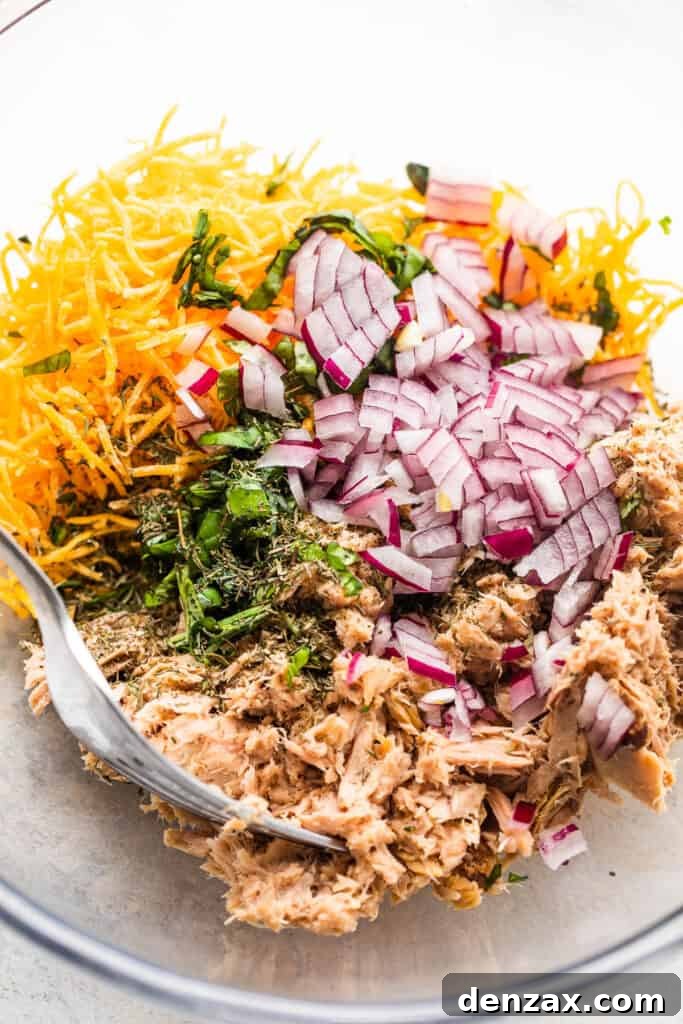 Crispy Tuna Melt Grilled Cheese Sandwich Recipe 4 flaked tuna in a glass bowl with shredded cheddar cheese, diced red onions, and fresh herbs.