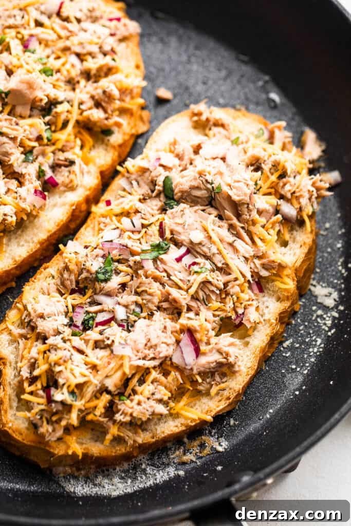 Crispy Tuna Melt Grilled Cheese Sandwich Recipe 5 bread slices topped with flaked tuna and cooking in a black skillet