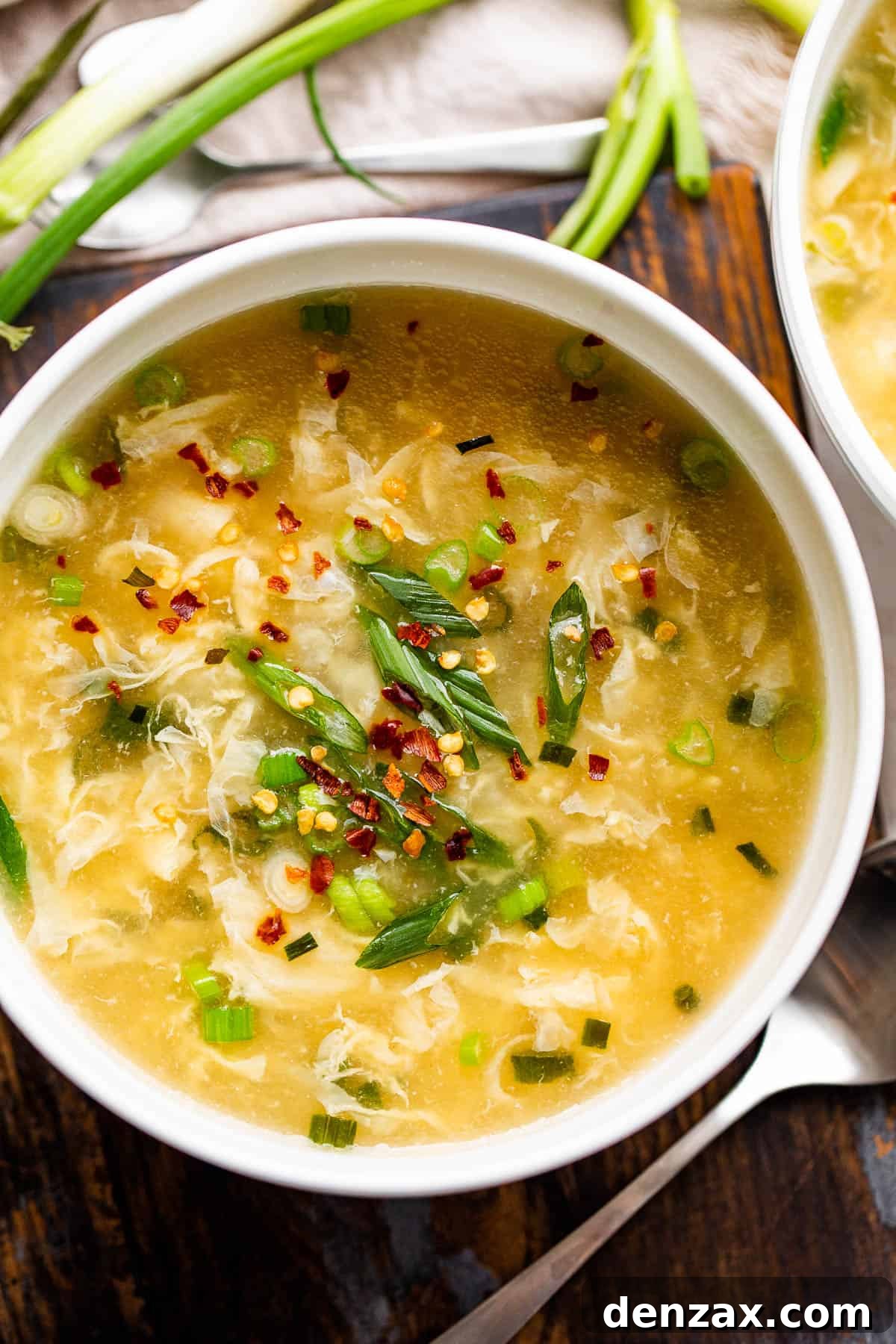 Whip up this simple egg drop soup in just 15 minutes—it might even taste better than the one from your go-to Chinese spot! overhead shot of a bowl with eggdrop soup garnished with green onions and red pepper flakes