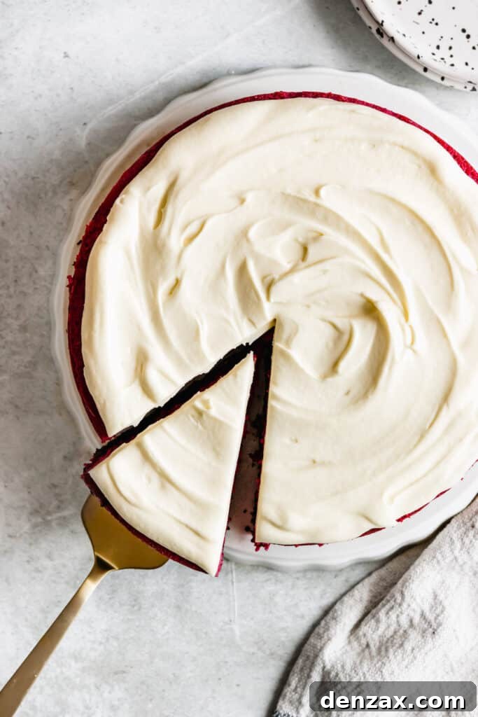 A Frosted Red Velvet Cheesecake Shown From the Top with One Slice Being Removed