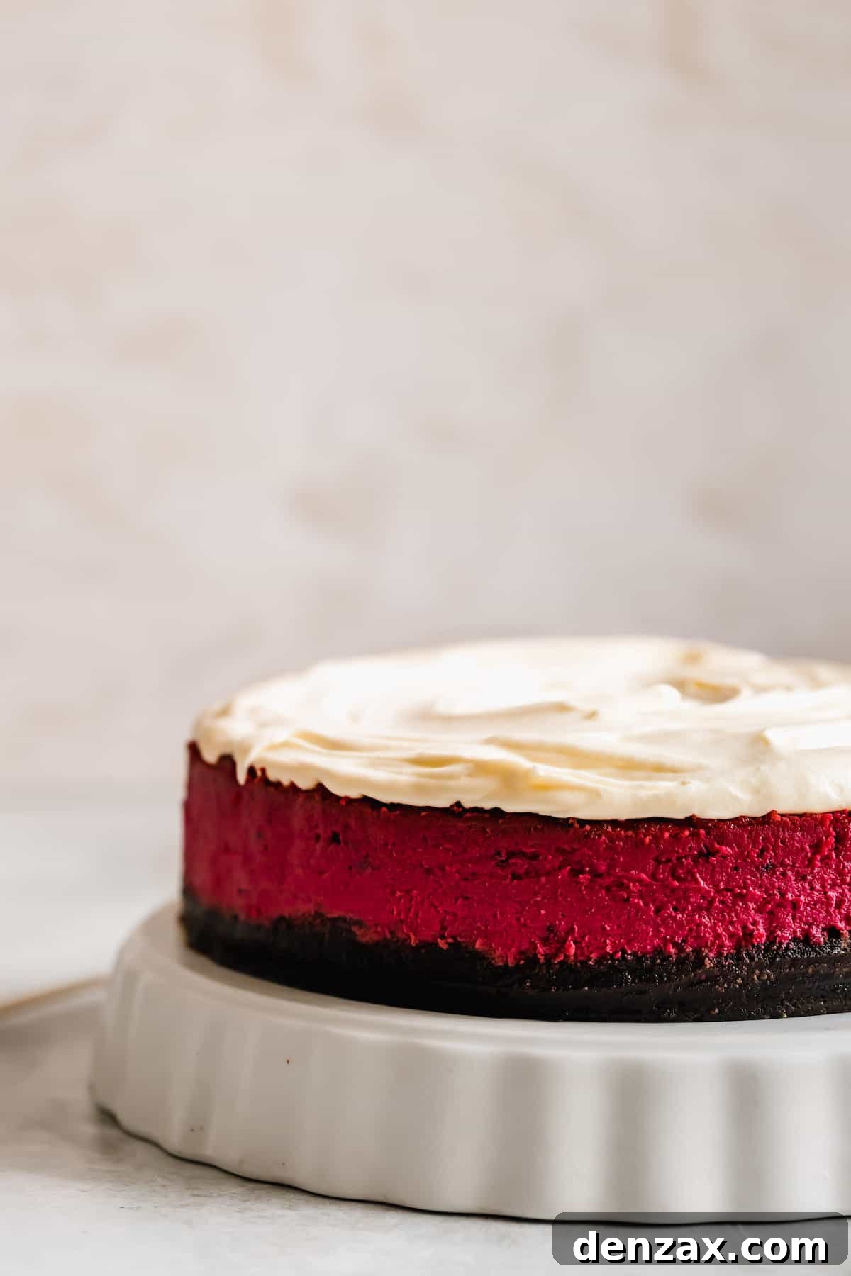 A Vibrant Red Velvet Cheesecake on a Cake Stand with a White Background