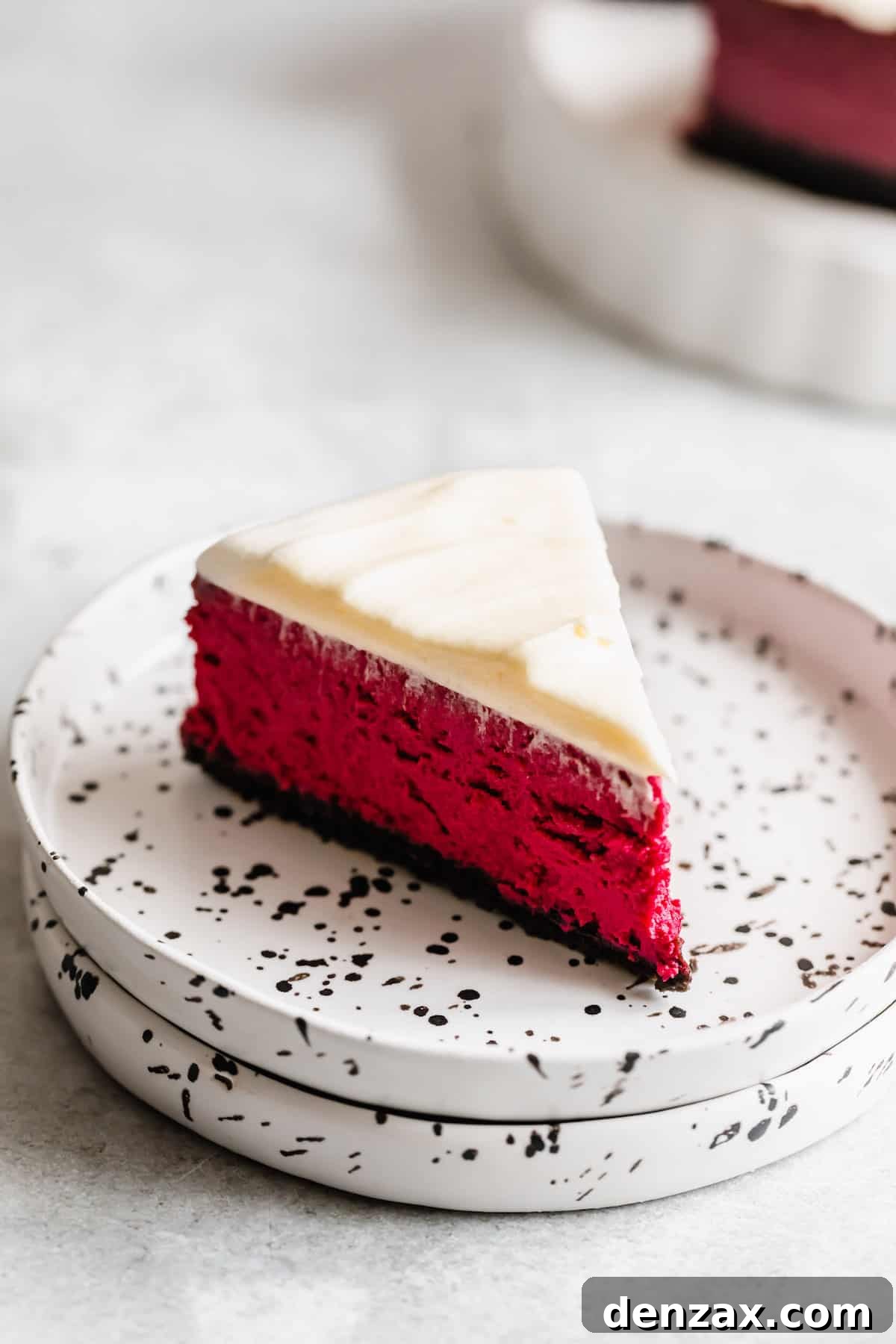 A Slice of Homemade Cheesecake with Oreo Crust and Cream Cheese Frosting on a Dessert Plate