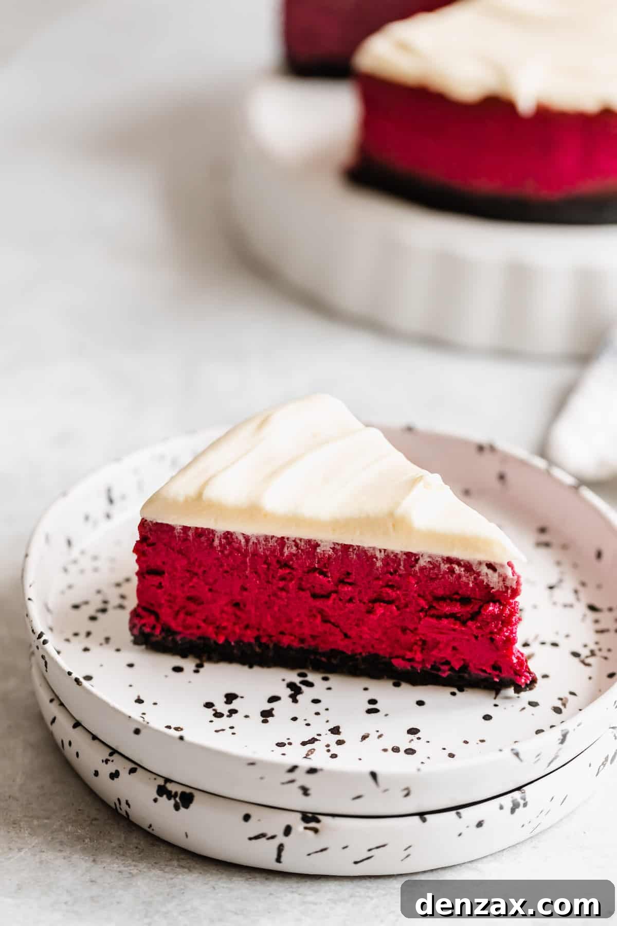 A Piece of Red Velvet Cheesecake on a Black and White Speckled Plate