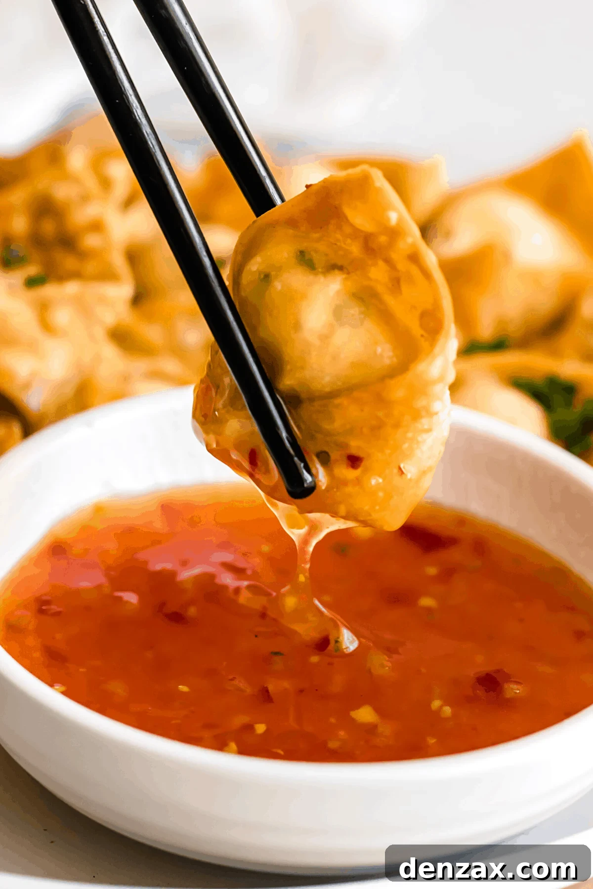 Crispy Crab Rangoon Wontons Recipe: Creamy Crab-Filled Appetizers 2 holding chopsticks and dipping crab rangoon wonton in dipping sauce