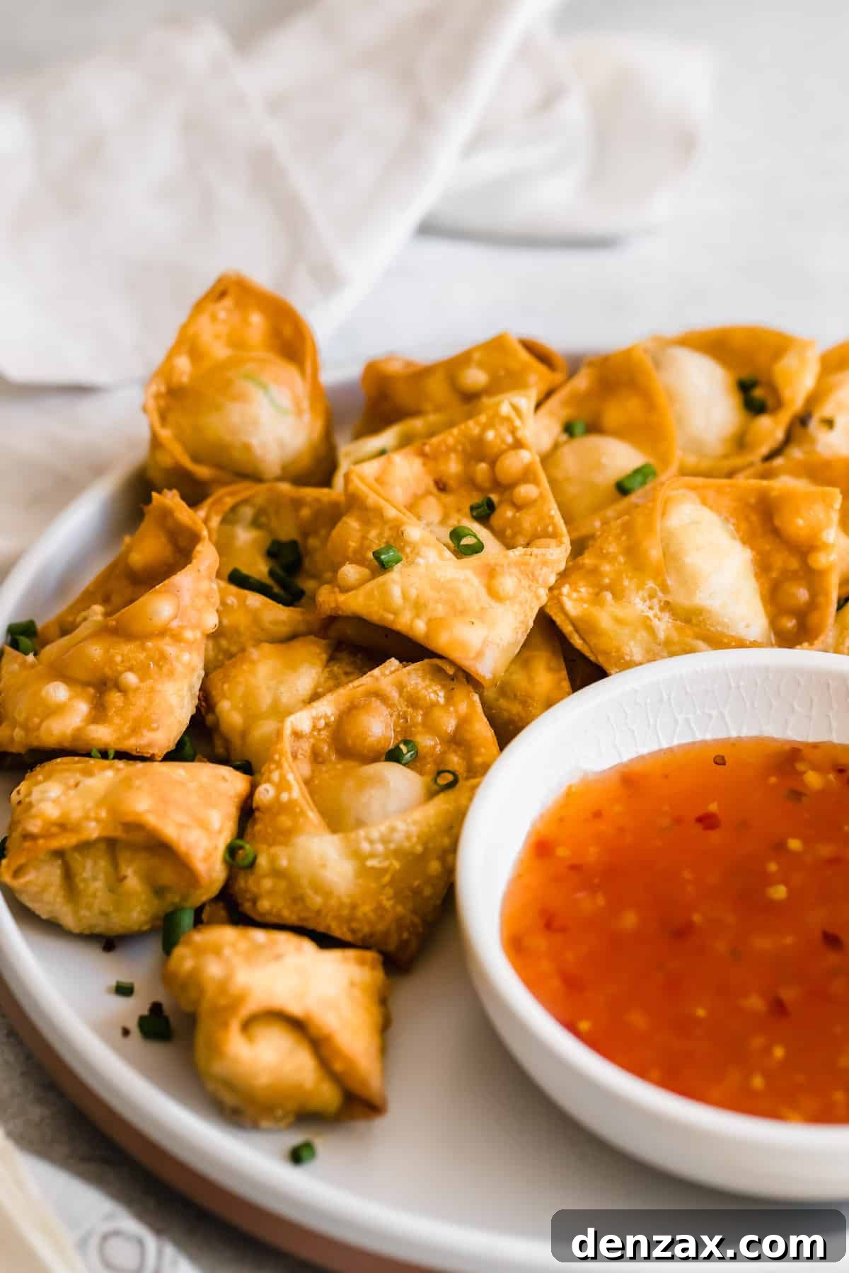 Crispy Crab Rangoon Wontons Recipe: Creamy Crab-Filled Appetizers 9 Crab rangoons on a white plate served with dipping sauce.