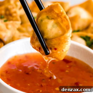 Crispy Crab Rangoon Wontons Recipe: Creamy Crab-Filled Appetizers 11 holding chopsticks and dipping crab rangoon wonton in dipping sauce