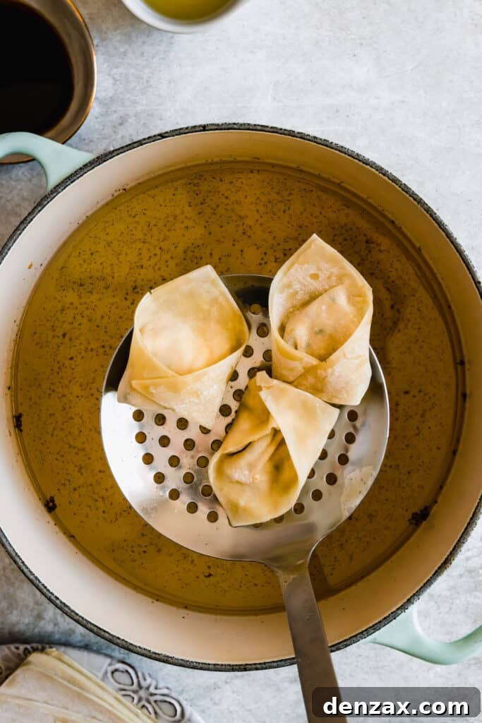 Crispy Crab Rangoon Wontons Recipe: Creamy Crab-Filled Appetizers 7 Crab rangoon wontons being fried