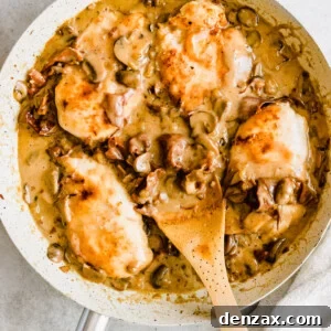 Chicken in a creamy marsala sauce with a wooden serving spoon.