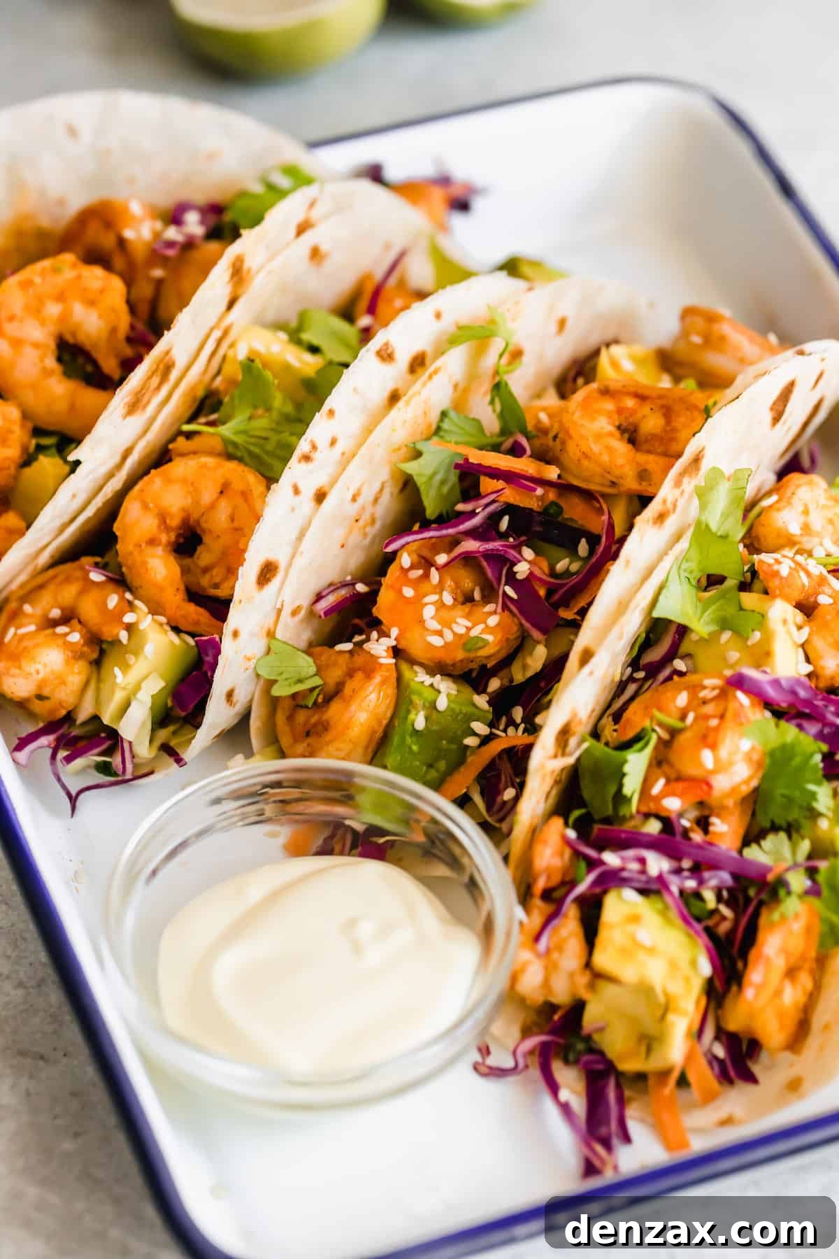 A Platter Holding Four Shrimp Tacos and a Dish of Dressing