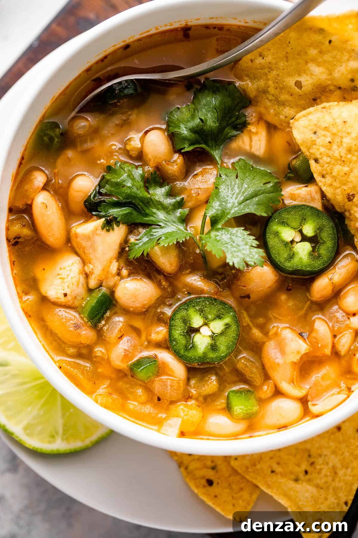 chicken chili in a bowl topped with jalapenos, cilantro, and tortilla chips