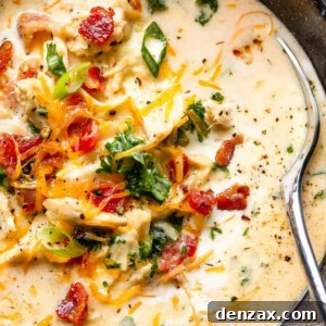 crack chicken soup in a black bowl garnished with bacon crumbles, scallions, and shredded cheese