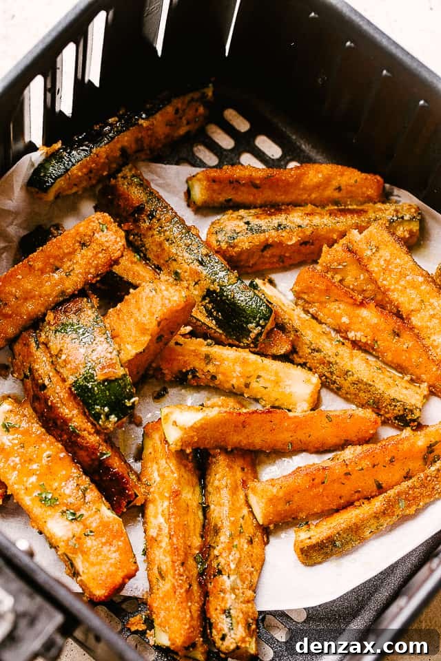 Fried zucchini in the basket of an air fryer.