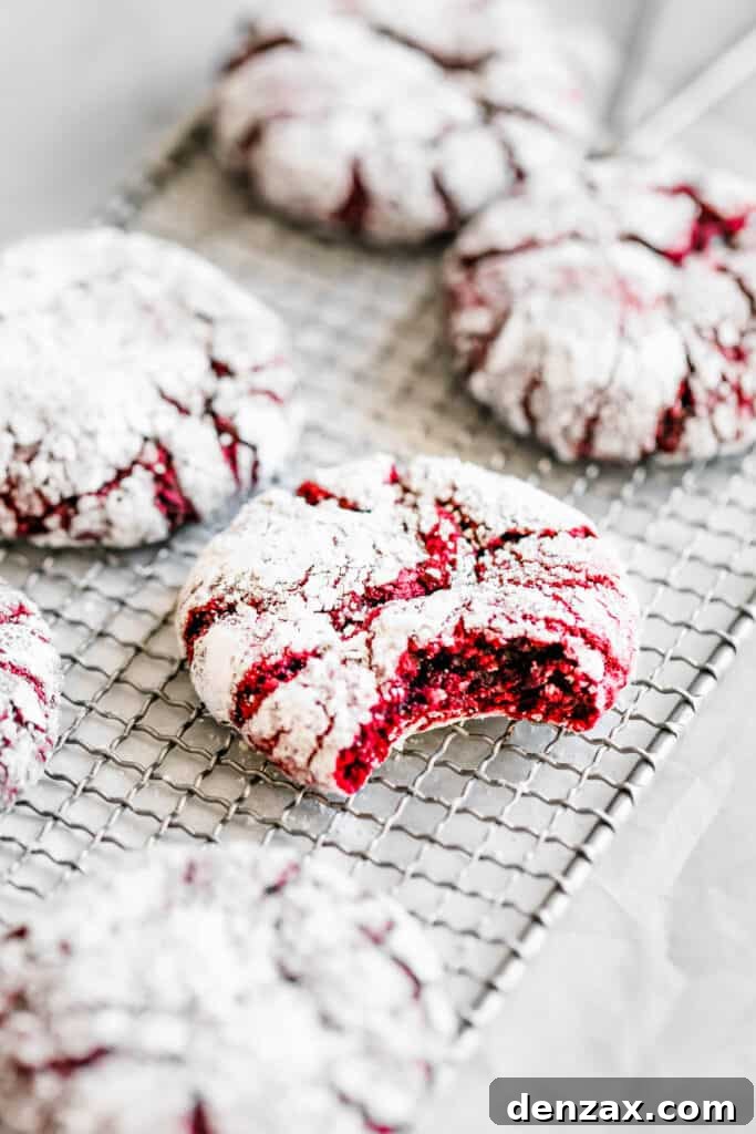 Six Red Velvet Crinkle Cookies on a Wire Cooling Rack with One Cookie Missing a Bite