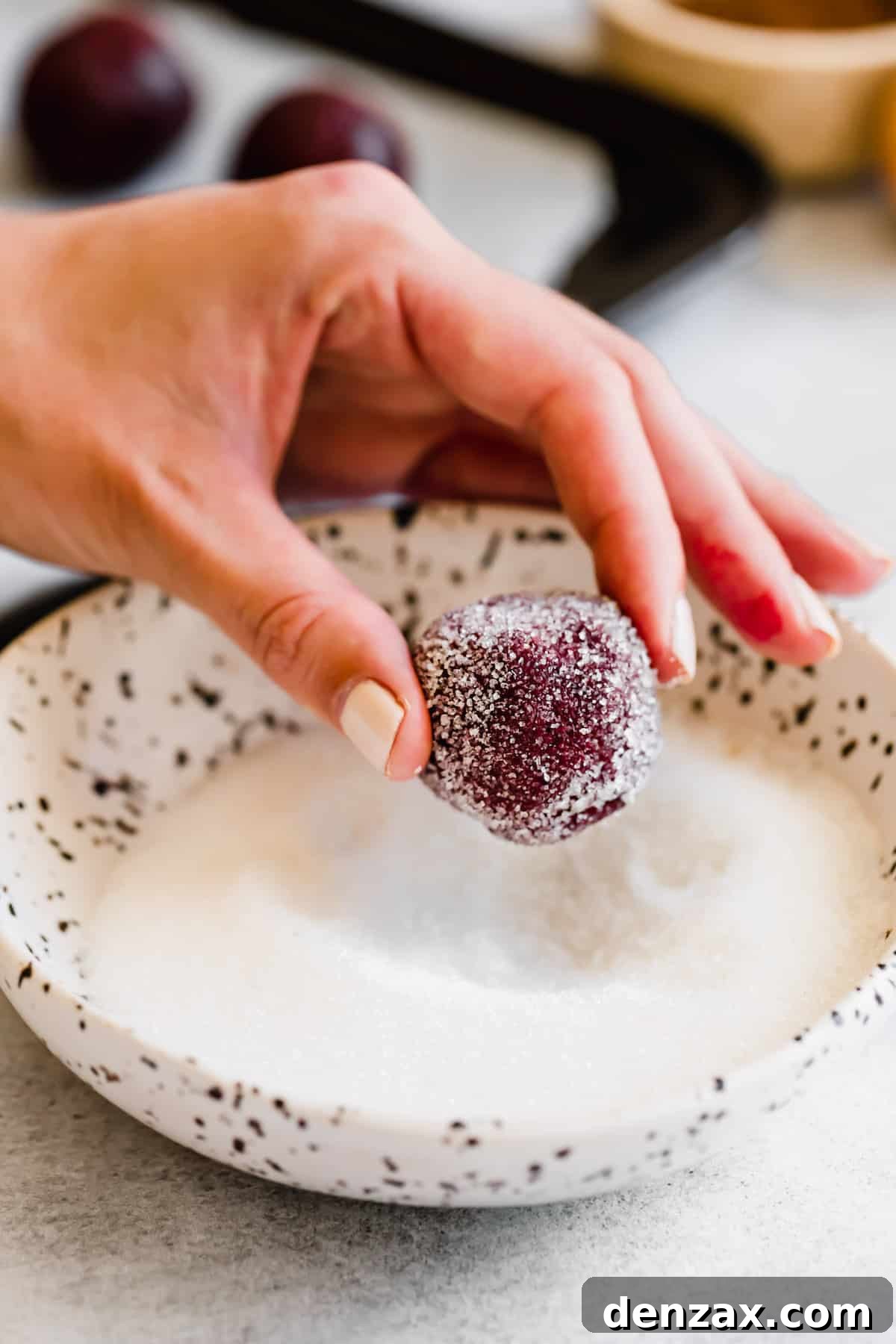 A Hand Holding a Sugar-Coated Ball of Red Velvet Cookie Dough