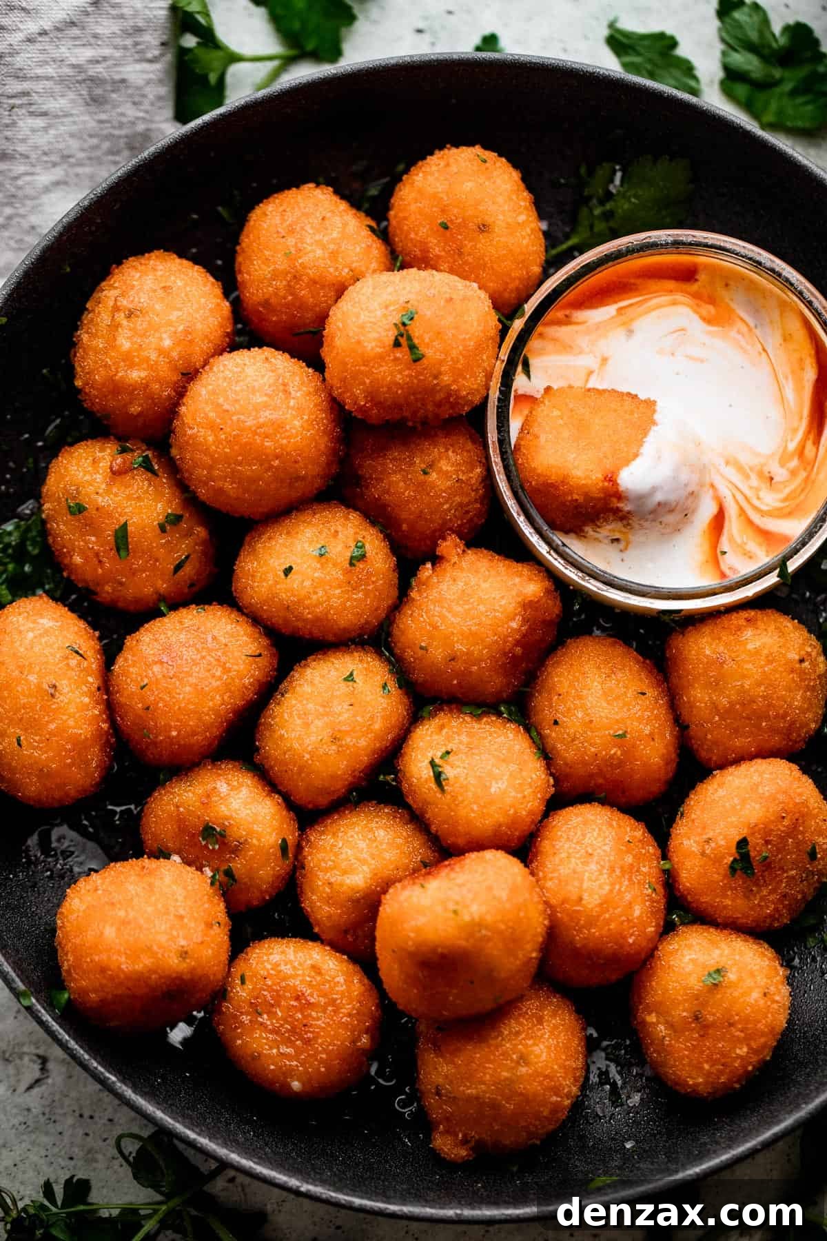 overhead shot of Jalapeno Popper Balls in a black bowl with a Dipping Sauce