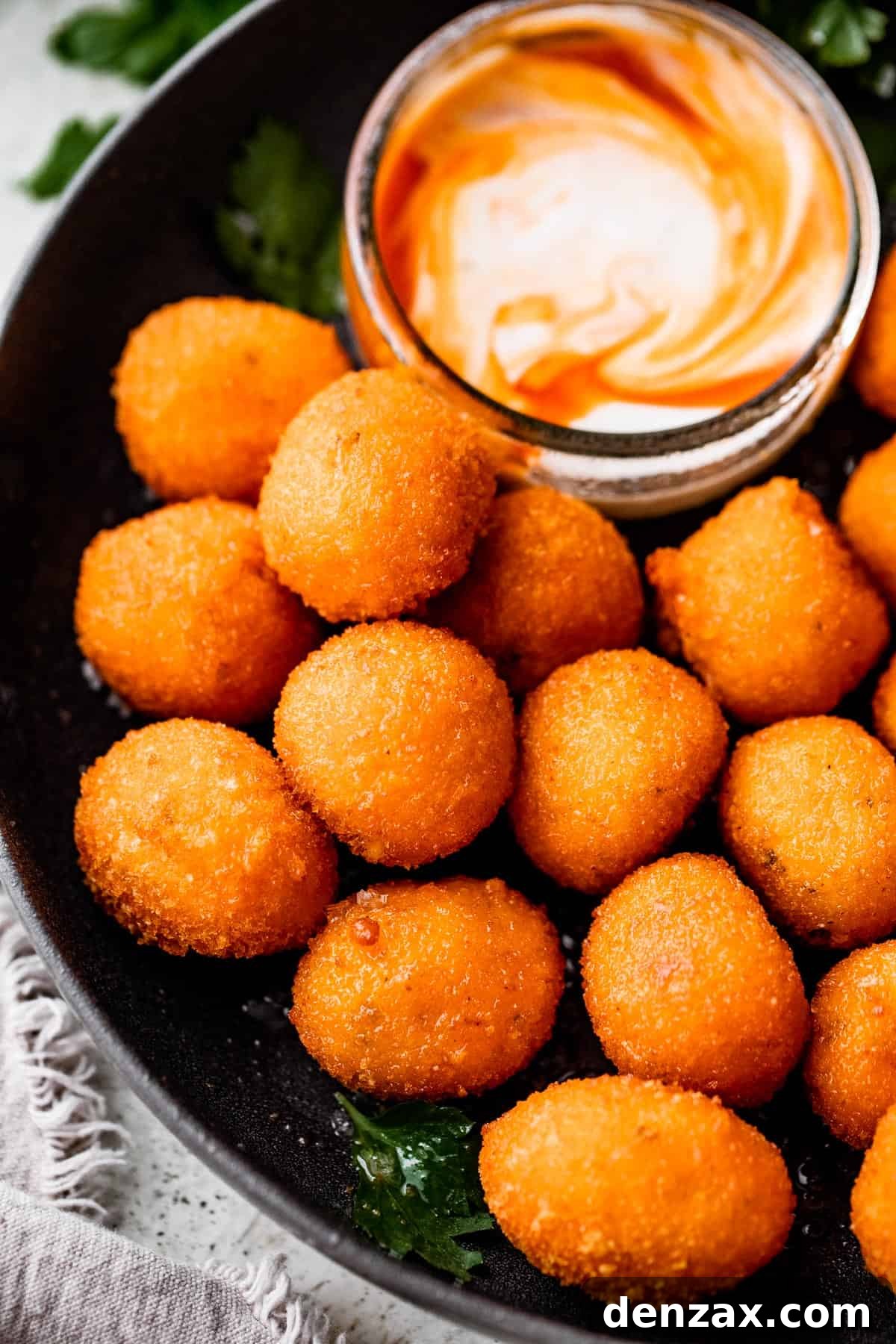 up close shot of air fryer cooked jalapeno popper balls and a dipping sauce placed next to them.