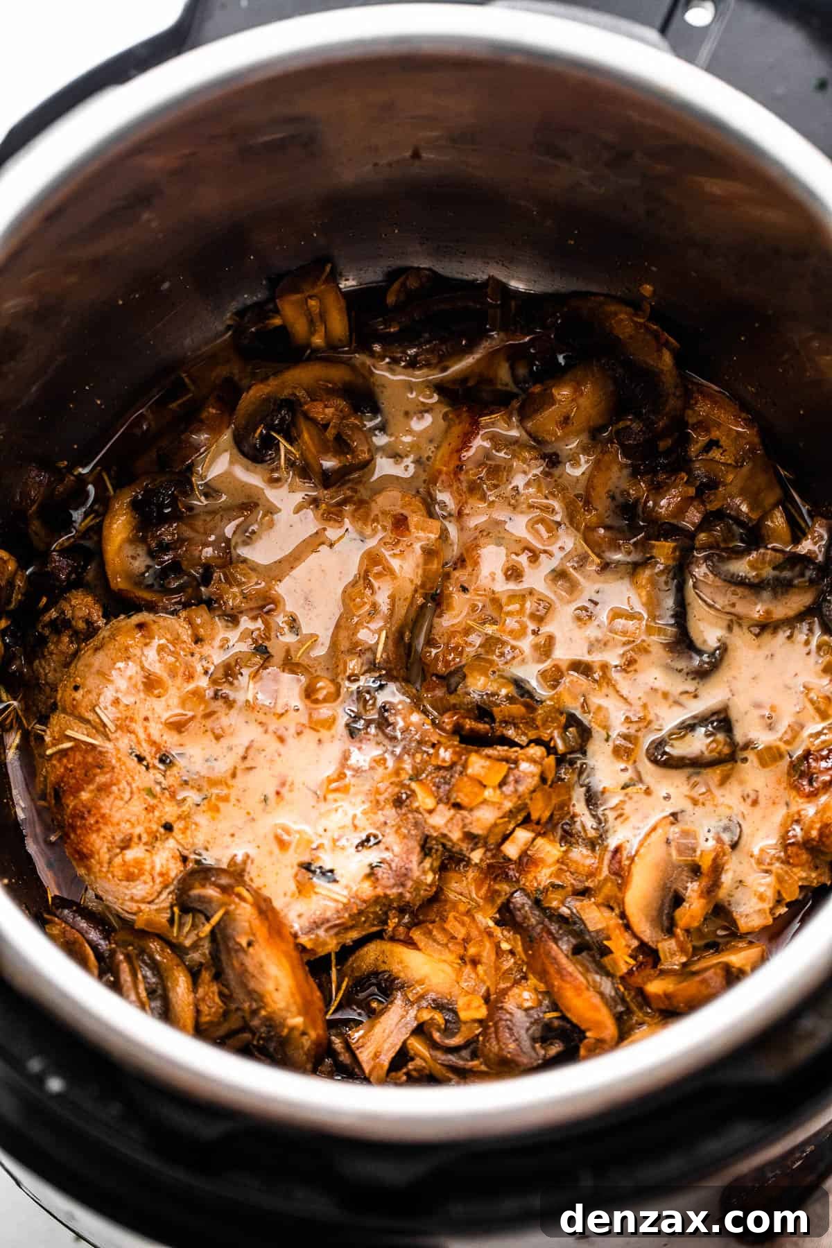 overhead shot of two pork chops in the instant pot topped with mushroom gravy sauce