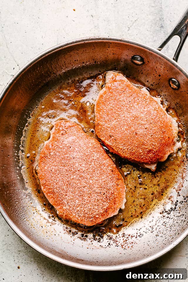 Frying smothered pork chops in a skillet.