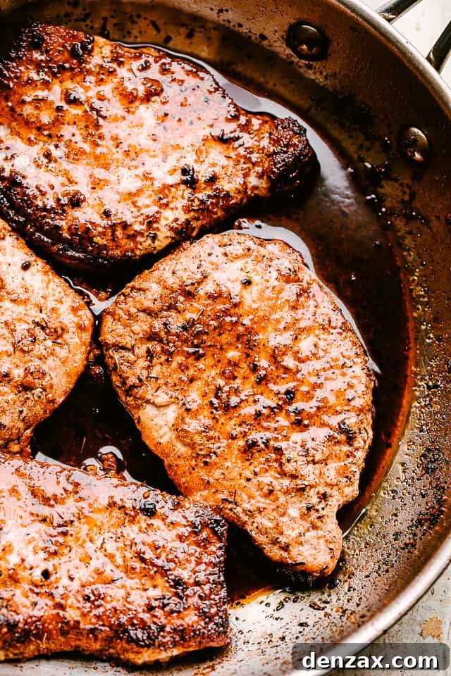 Pan fried pork chops in a skillet.