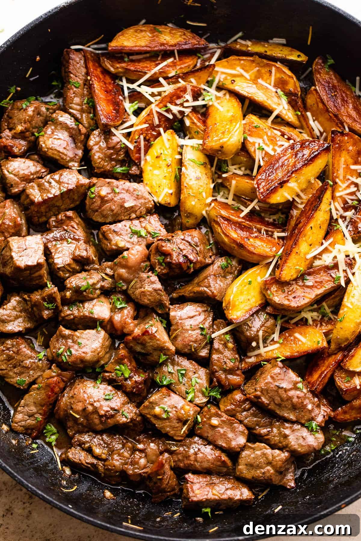 overhead shot of sirloin steak bites and quartered gold potatoes in a skillet