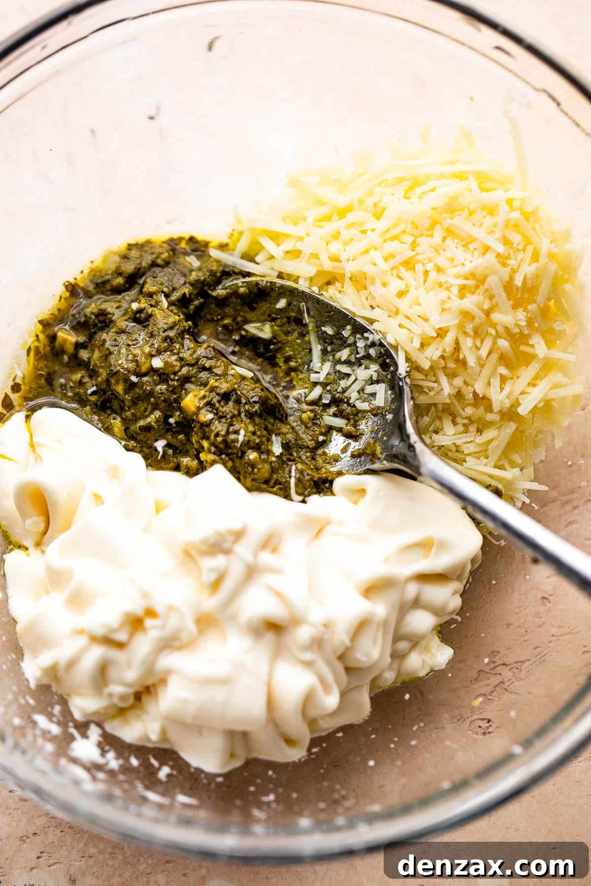 mixing together basil pesto, mayonnaise, and parmesan cheese