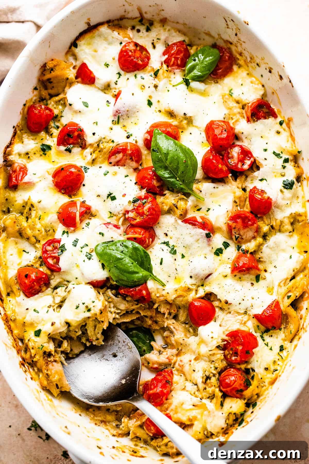 spooning out chicken caprese casserole from the baking dish
