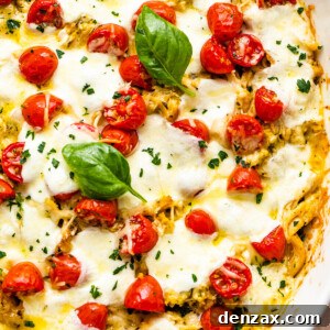 chicken caprese casserole in a white baking dish topped with basil leaves and cherry tomatoes