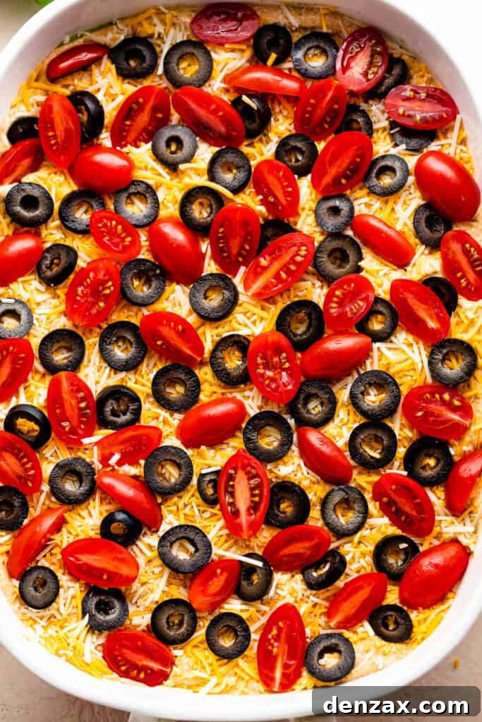overhead shot of a white baking dish with halved cherry tomatoes and sliced olives