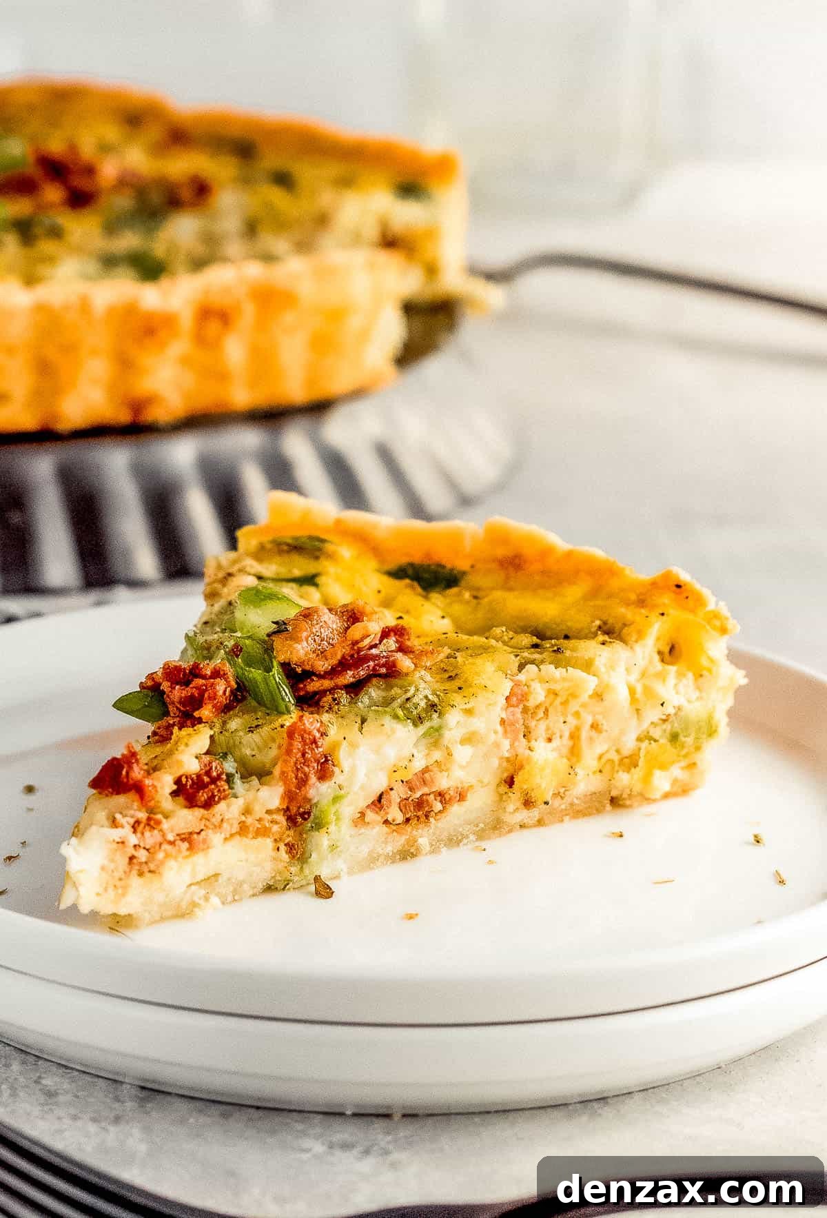 A Close-Up Shot of a Slice of Bacon Quiche Lorraine on a white plate