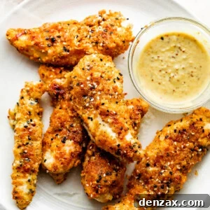 Everything Bagel Chicken Tenders arranged on a round plate and served with honey mustard dipping sauce