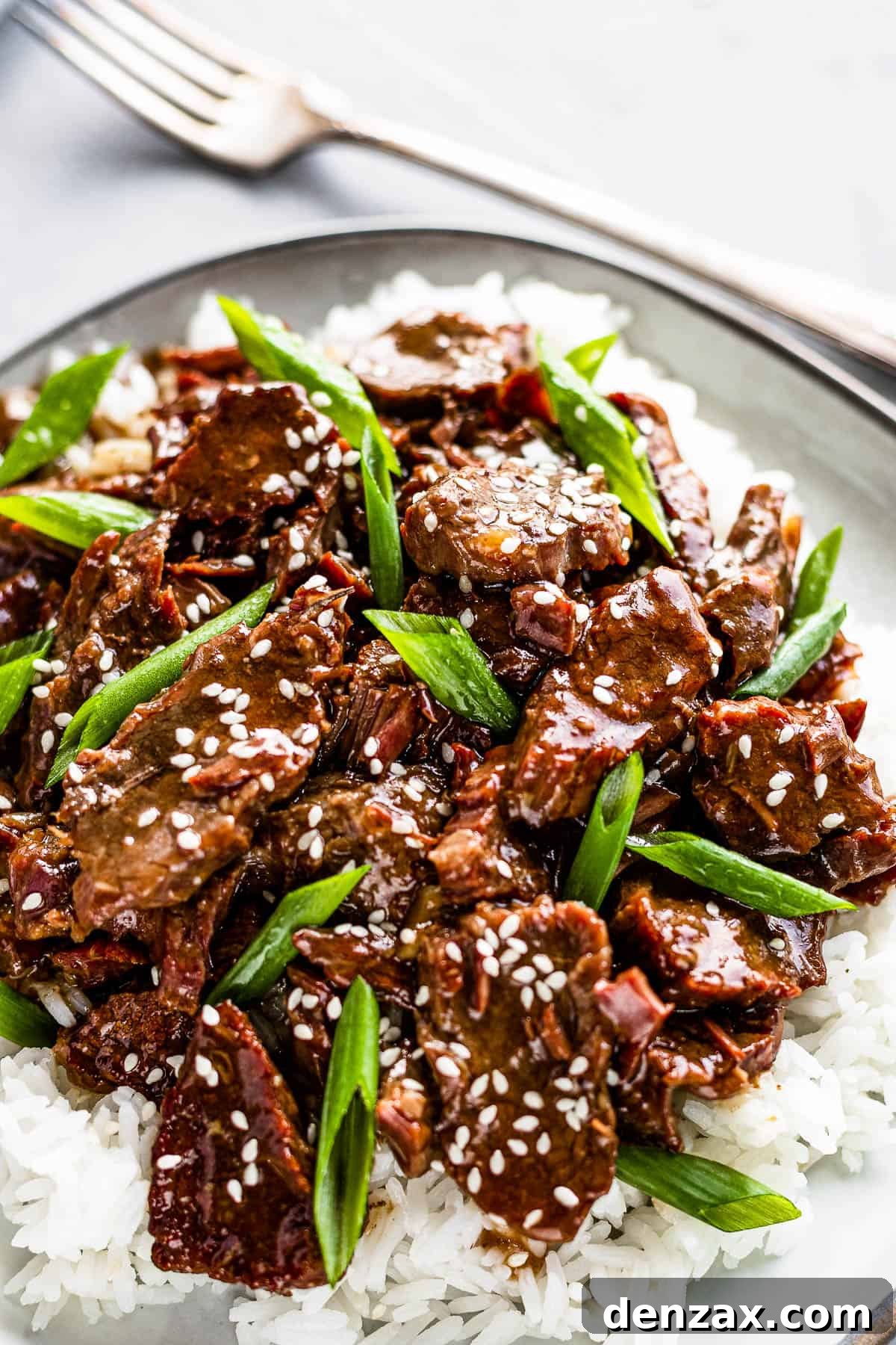Instant Pot Mongolian Beef Over White Rice on a Gray Plate with a fork on the side