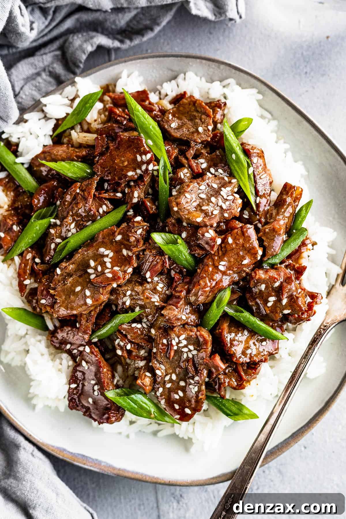 Instant Pot Mongolian Beef Over White Rice on a Gray Plate with a fork on the plate
