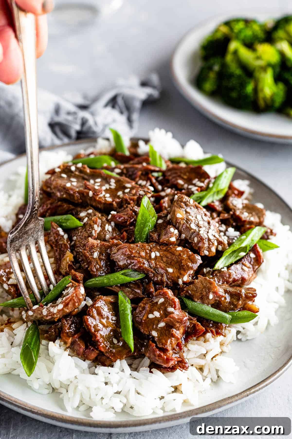 A Metal Fork Digging Into a Plate of Instant Pot Mongolian Beef Over White Rice