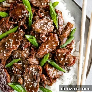 Instant Pot Mongolian Beef Over White Rice on a Gray Plate with a Pair of Wooden Chopsticks