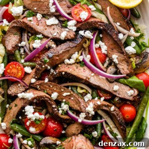 Steak Salad served on a long plate topped with cheese crumbles, tomatoes, and mushrooms