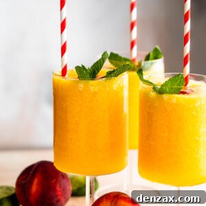 three glasses filled with peach daiquiris and garnished with mint, peach slices, and straws