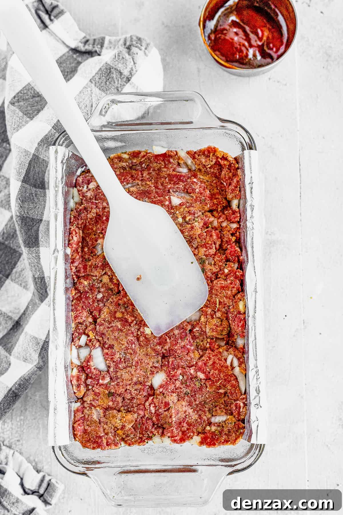 A Spatula Spreading the Meatloaf Mixture Into a Foil-Lined Pan