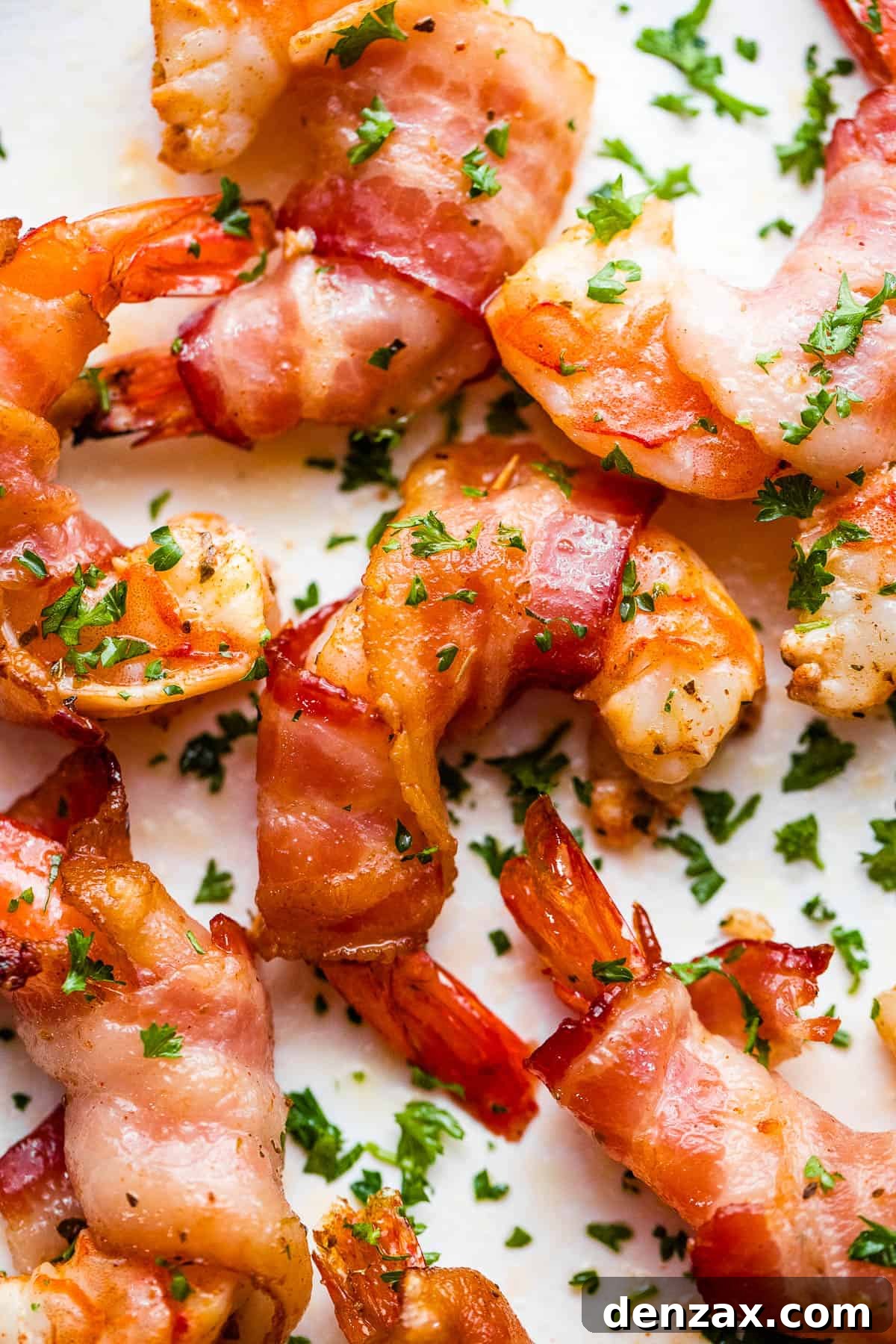 bacon wrapped shrimp arranged on a white plate and garnished with parsley