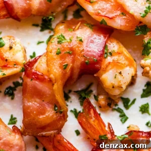 up close photo of bacon wrapped shrimp arranged on a white plate and garnished with parsley