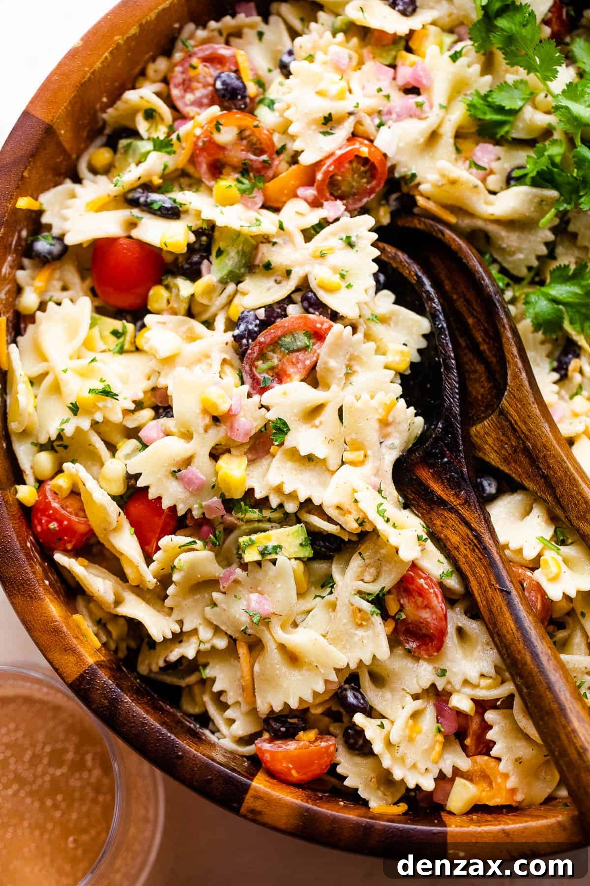 fiesta pasta salad in a wooden salad bowl with two wooden spoons