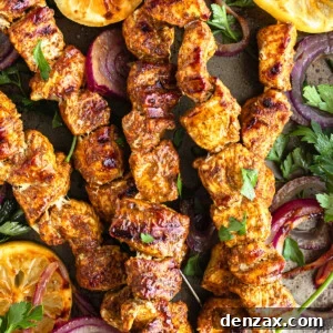 Five Shawarma Grilled Chicken Skewers on a Metal Pan with Onions, Lemon Slices and More