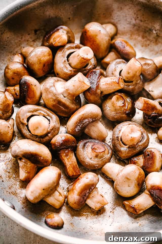 Placing button mushrooms in a skillet to cook.