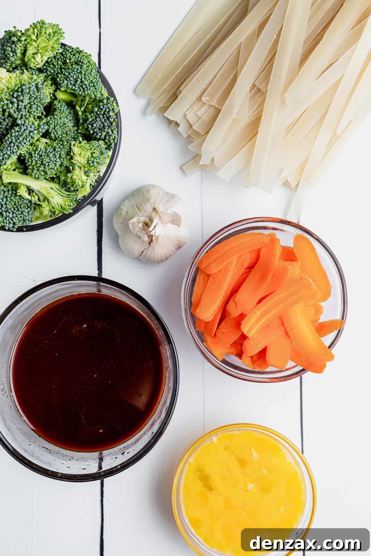 Broccoli, Flat Rice Noodles, Carrot Slices and the Rest of the Ingredients on Top of a White Picnic Table