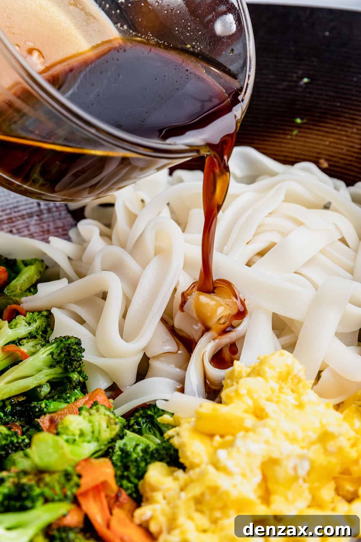 Pad See Ew Sauce Being Added to the Noodles, Eggs and Veggies in the Bowl