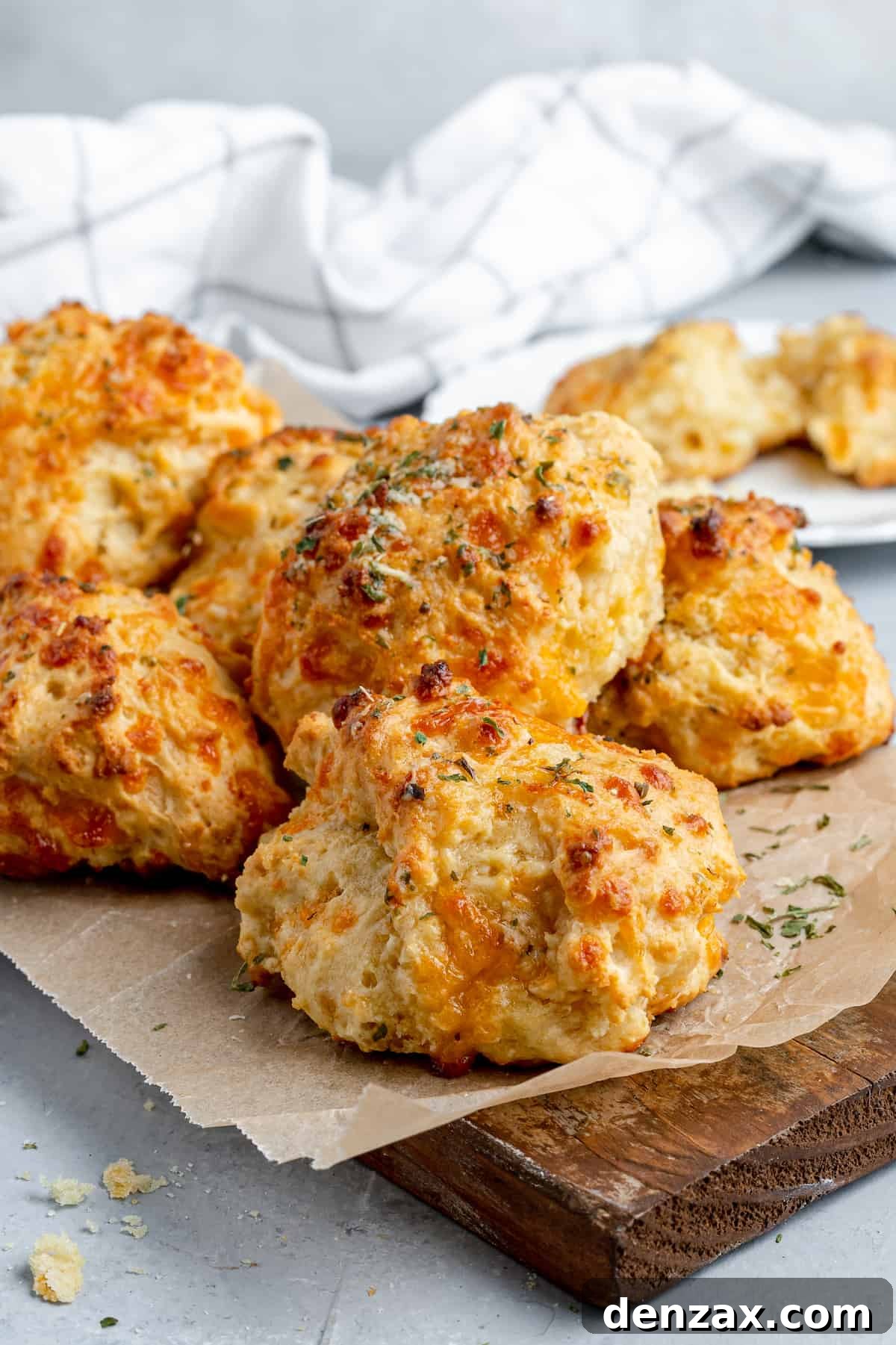 Six Air Fryer Biscuits on a Piece of Parchment Paper Over a Wooden Board