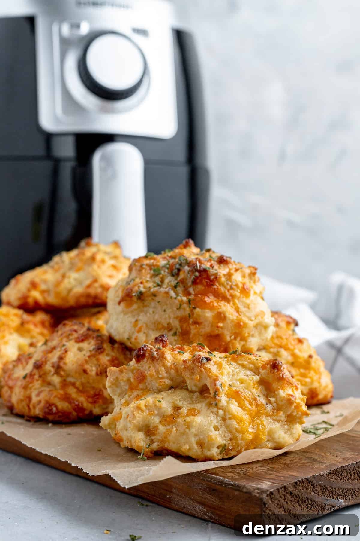 A Pile of Red Lobster Biscuits on a Cutting Board with an Air Fryer in the Background