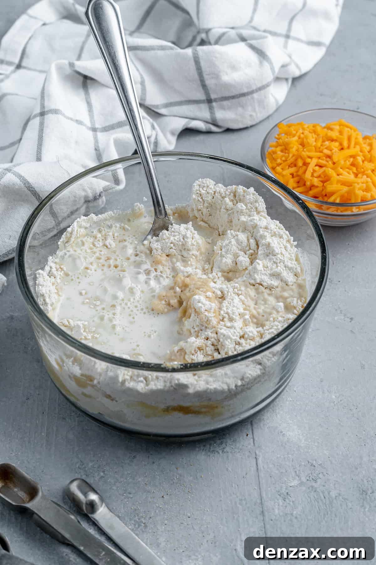 Bisquick Mix, Milk and Butter in a Bowl Beside a Dish of Shredded Cheddar